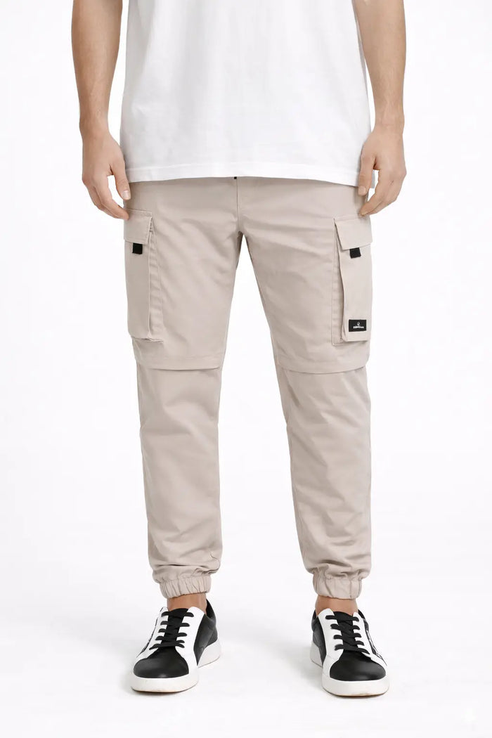 Adrian carbon beige utility cargo pants with zip-off convertible knees, multi-pockets, and elastic cuffed hems.