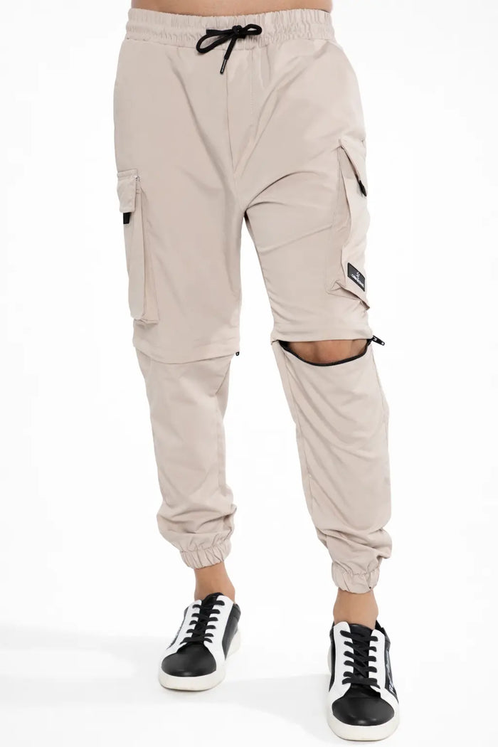 Tan Adrian multi-pocket cargo pants featuring zip-off convertible knees, drawstring waist, and utility streetwear style.