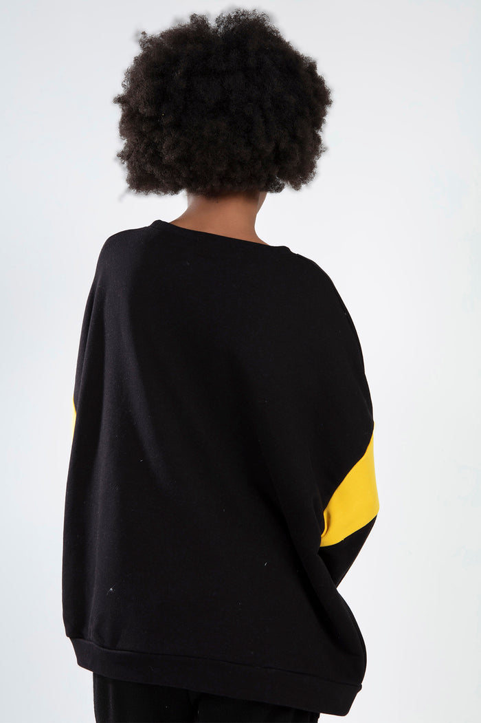 Back view of the ALPES Black Ribbed Crop Top featuring oversized fit and bold yellow sleeve accents on a model.