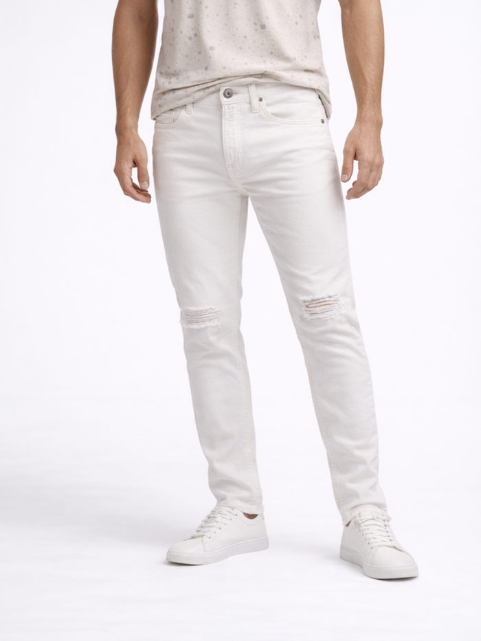 A person wearing light-colored distressed jeans paired with a speckled beige t-shirt and white sneakers.