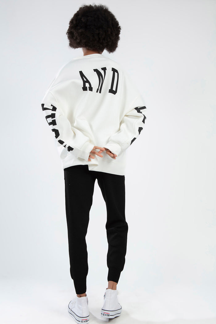 Back view of model in Ari white oversized sweatshirt with black 'AND' graphic and sleeve lettering.