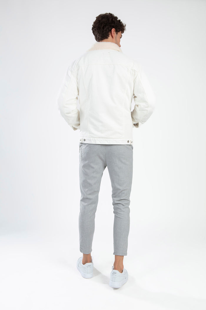 Back view of a man wearing the Ashton White Denim Jacket with a cream faux-fur collar and grey trousers.