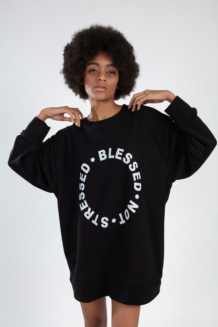 Model in oversized Carbon black sweatshirt featuring a circular Blessed Not Stressed graphic in white streetwear print.