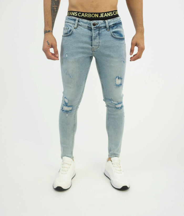 Men's light blue super skinny fit jeans with distressed details and ripped knees on a model wearing white sneakers.