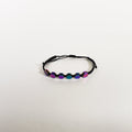 Unisex black braided rope bracelet featuring six iridescent, multi-color hexagonal beads on a clean white background.