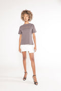 Model in a carbon gray Brooklyn graphic tee, white mini skirt, and black heels, showcasing an urban streetwear style.