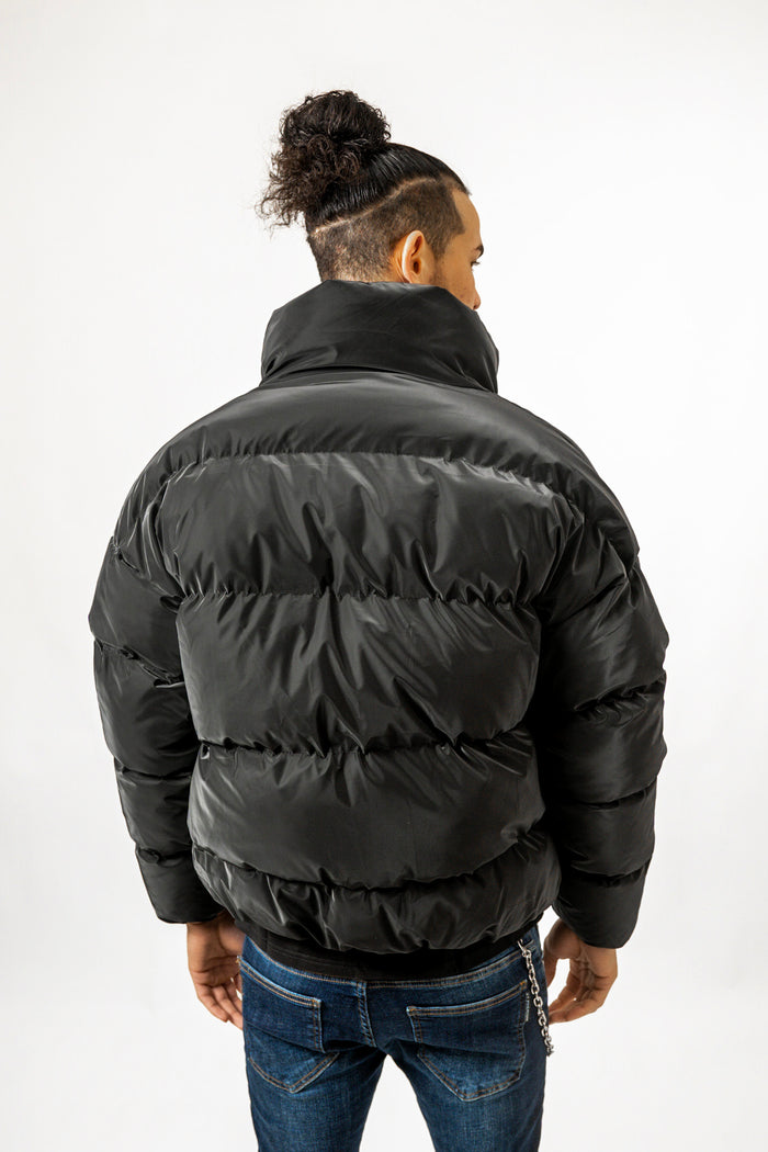 Rear view of Brooks black puffer coat featuring an oversized minimalist design and high collar for winter streetwear style.
