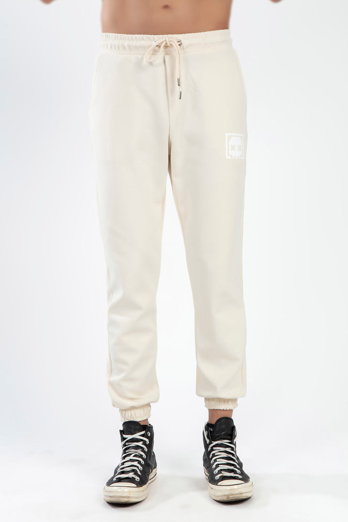 Chester cream streetwear jogger pants with drawstring waist and logo detail, paired with black high-top sneakers.
