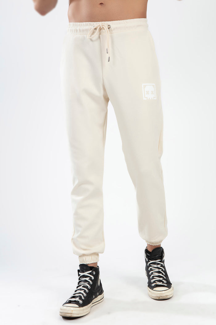Men's beige Chester streetwear jogger pants featuring a drawstring waistband, cuffed ankles, and a white skull logo.