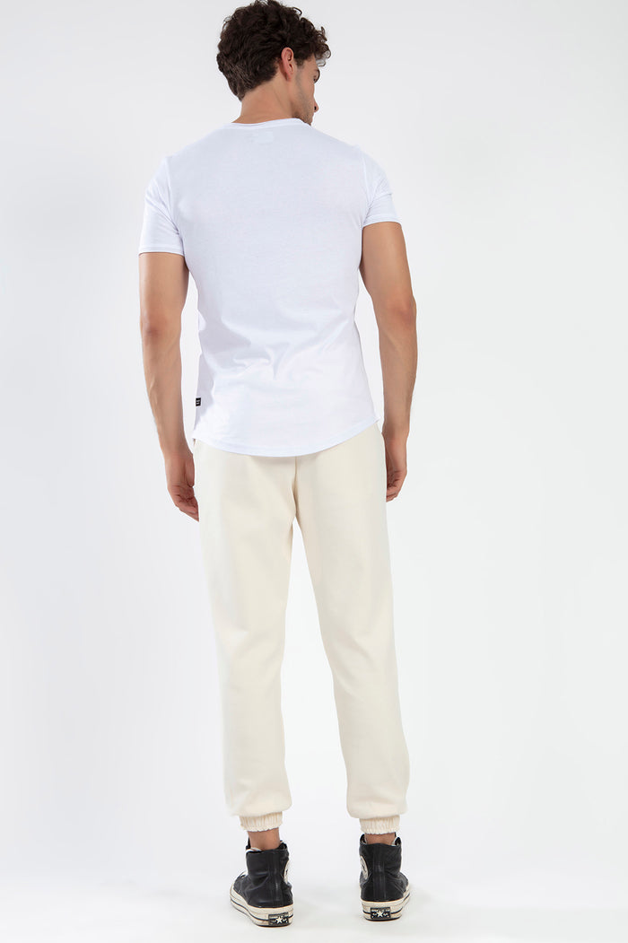 Back view of Chester beige relaxed-fit jogger pants with elastic cuffs, styled with a white t-shirt and high-top sneakers.