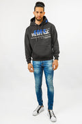 Man wearing Carbon Jeans black heritage streetwear hoodie with blue embroidery and slim-fit blue jeans.