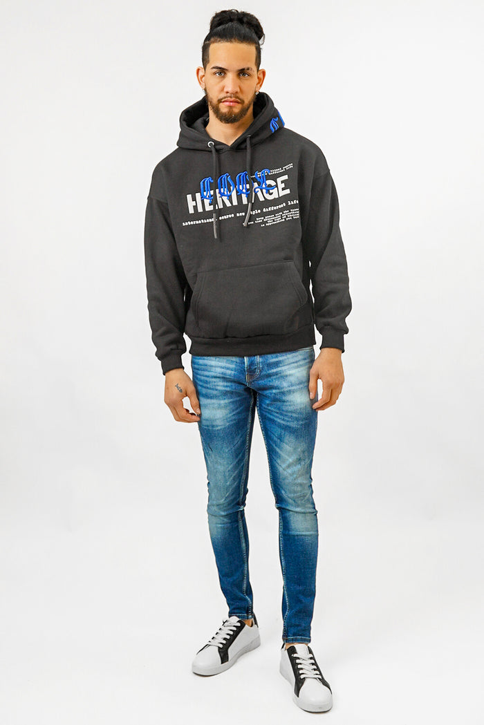Man wearing Carbon Jeans black heritage streetwear hoodie with blue embroidery and slim-fit blue jeans.