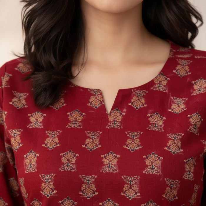 Close-up of maroon top V-notch neckline and gold block print detail