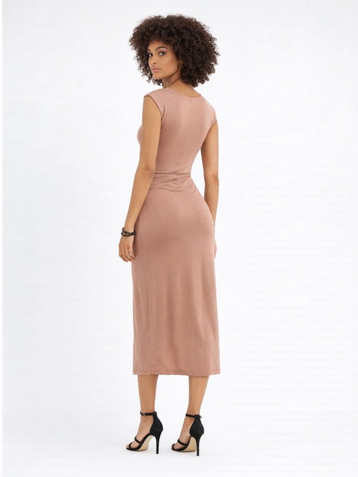 A model with curly hair poses in a fitted, knee-length dress, showcasing a sleek silhouette and strappy heels.