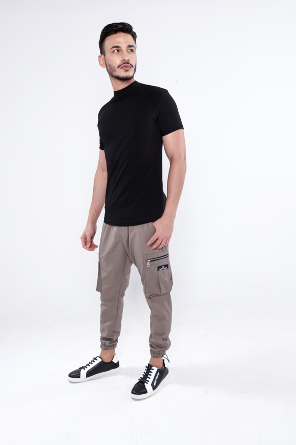 Model wearing a black mock-neck Damian shirt by Carbon Jeans paired with tan cargo pants and black and white sneakers.