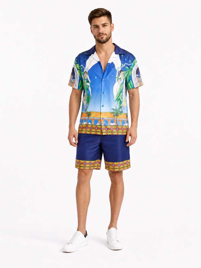A man stands wearing a colorful short-sleeve shirt with a vibrant tropical design and matching shorts.