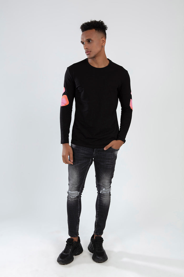 Men's black Element long sleeve streetwear shirt with pink elbow graphics, paired with distressed charcoal denim jeans.