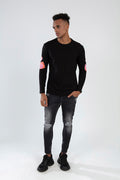 Men's black Element long sleeve streetwear shirt with pink elbow graphics, paired with distressed charcoal denim jeans.