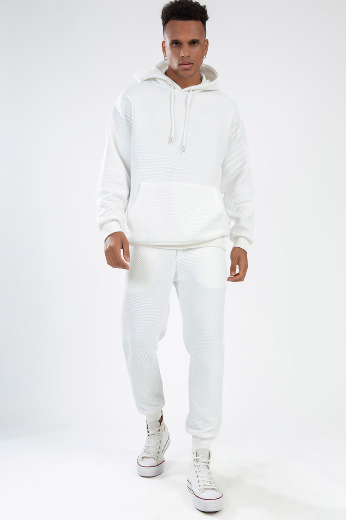 Man in white diagonal ribbed knit Eric Hoodie Set with matching streetwear joggers and high-top sneakers.