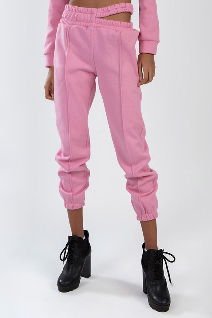 Pink streetwear joggers from the Eyes Pants Set featuring a cutout waistband and seam details with black platform boots.