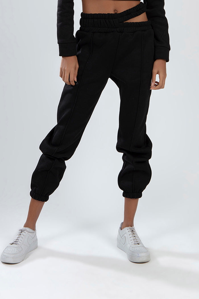 Model wearing black Eyes Pants Set with high-waist cutout joggers and matching long-sleeve crop top.