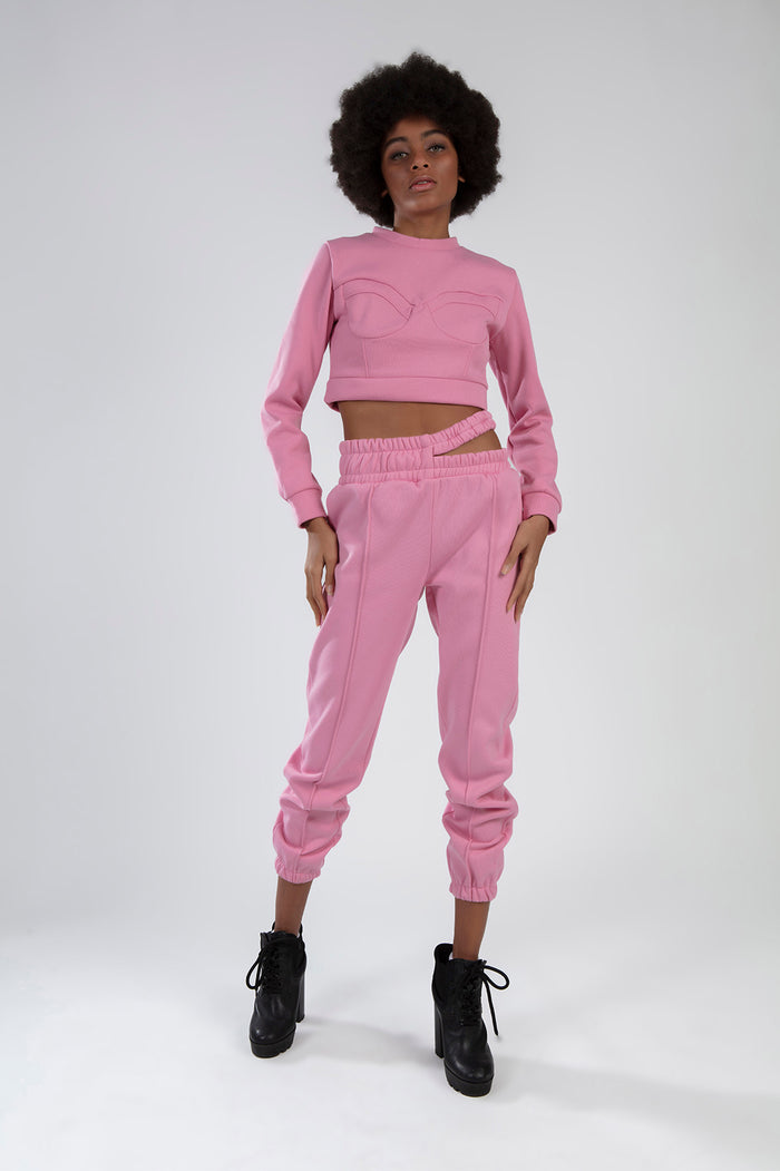 Model wearing pink Eyes Top Set cropped sweatshirt with eye-detail stitching and matching cutout sweatpants.