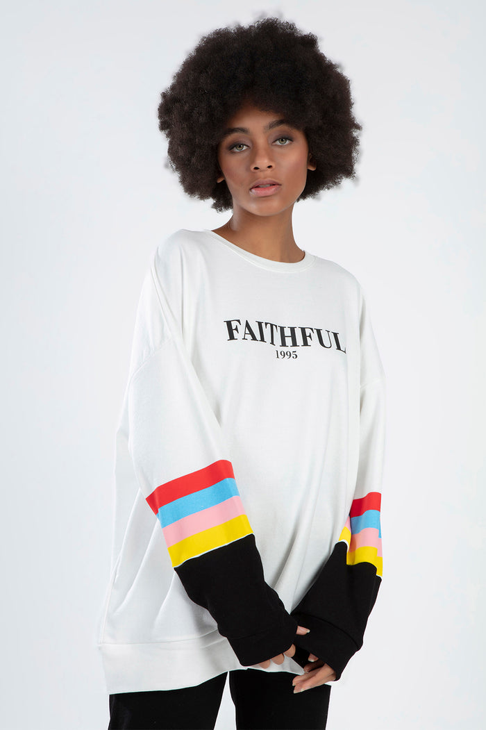 Model wearing FAITHFUL 1995 white oversized sweatshirt with multi-colored striped sleeves and black cuffs.