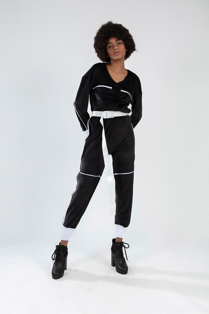 Finaley Black Romper with white belt, zipper accents, and contrast cuffs worn by a model in black platform boots.