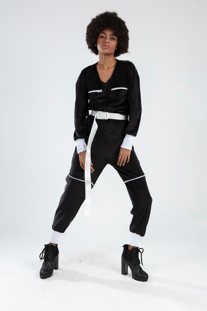 Model in Finaley black velvet romper with white belt, zipper details, and white cuffs for a trendy streetwear OOTD look.