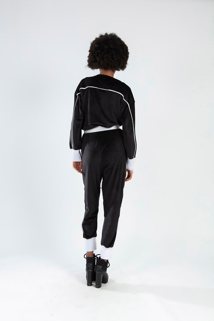 Back view of Finaley Romper in black velvet with white stripes and trim, featuring a sporty long-sleeve streetwear fit.
