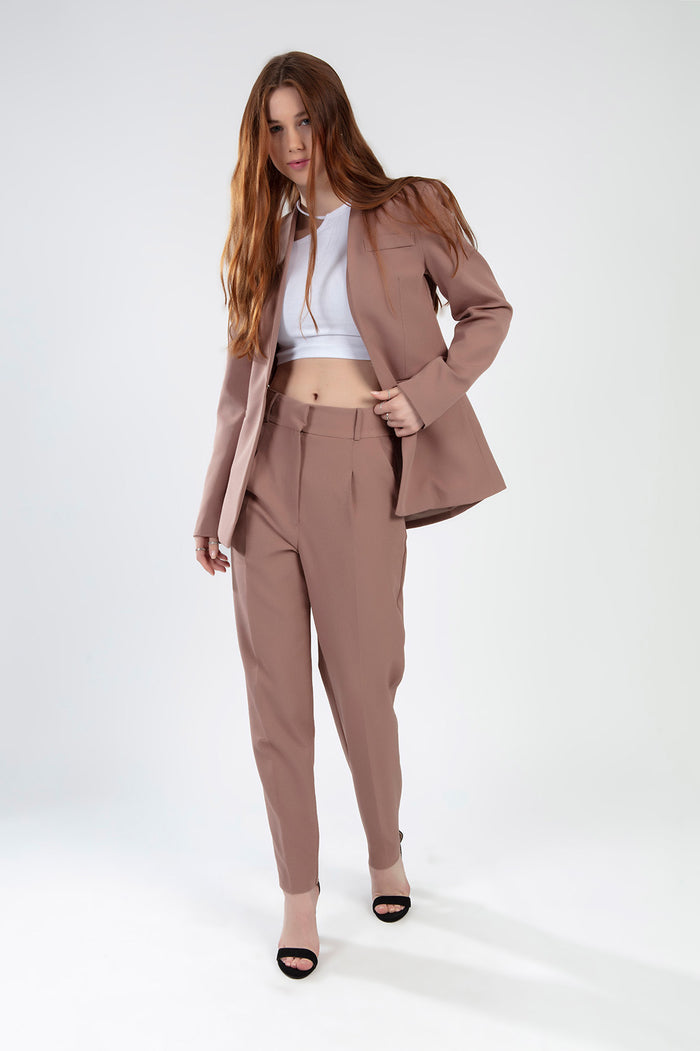 Model wearing the Fiona Pants Set in wild mushroom, featuring high-waisted pleated trousers and a matching blazer.