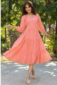 Woman wearing a flowing peach floral maxi dress with long sleeves outdoors