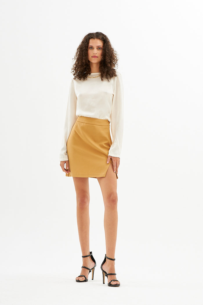 Model in pearl satin Fran crop top with gold chain necklace detail and mustard yellow mini skirt.