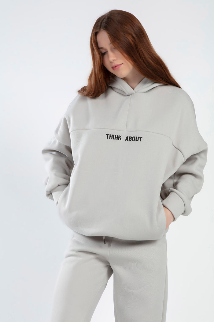 Model in Freya light grey oversized hoodie and matching joggers set with 'THINK ABOUT' text on chest.