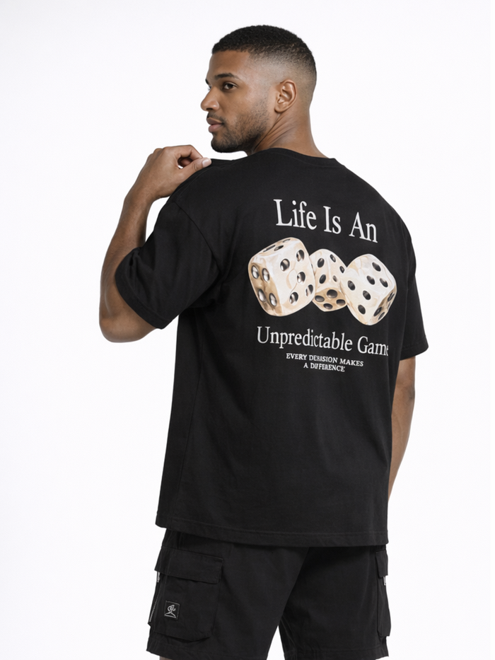 A man wearing a black t-shirt with a graphic of dice and text about life's unpredictability on the back.