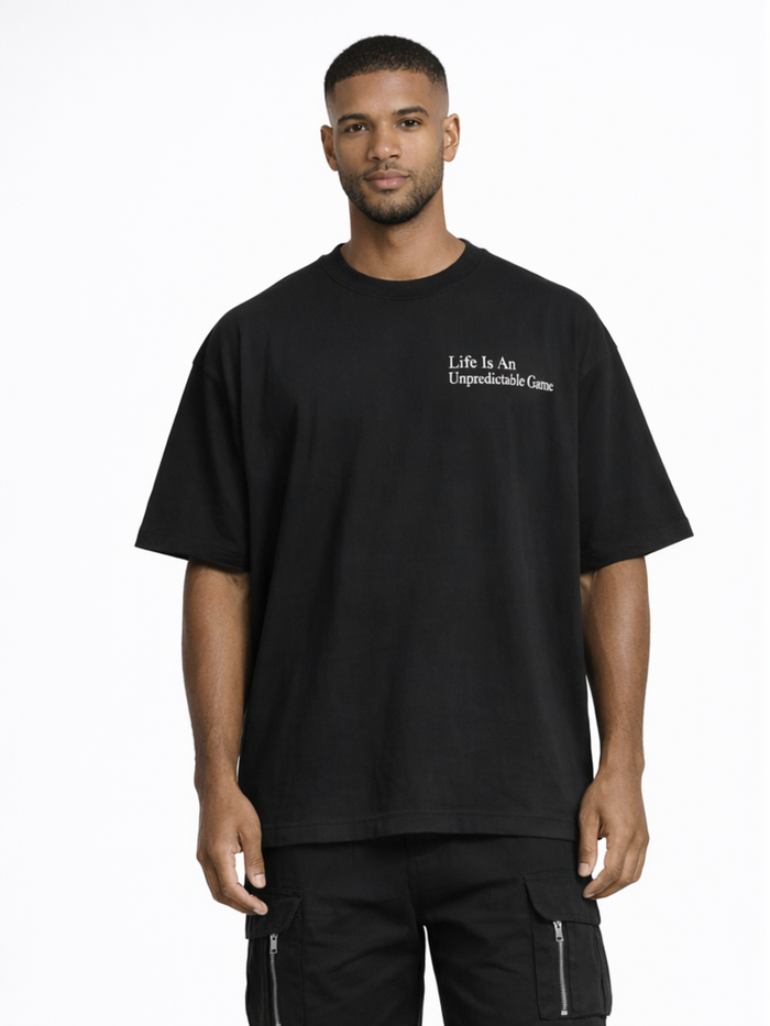 A man wearing a loose-fitting black t-shirt with a white text graphic on the chest, paired with black cargo pants.