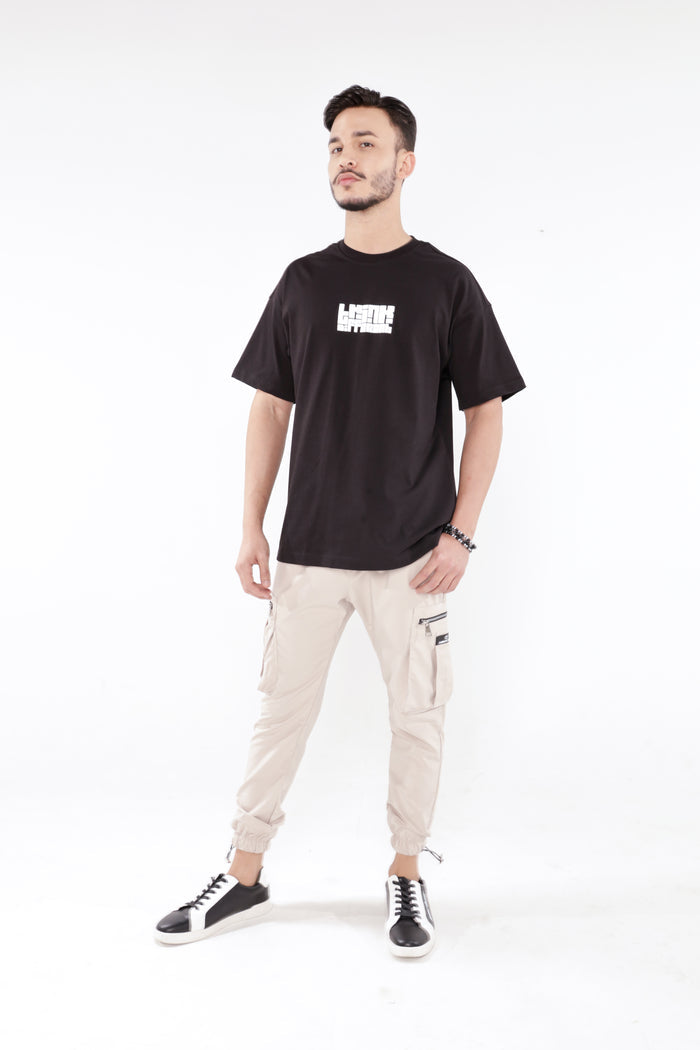 Model wearing Gary Cargo Pants in stone with side utility pockets and cuffed ankles for an urban streetwear look.