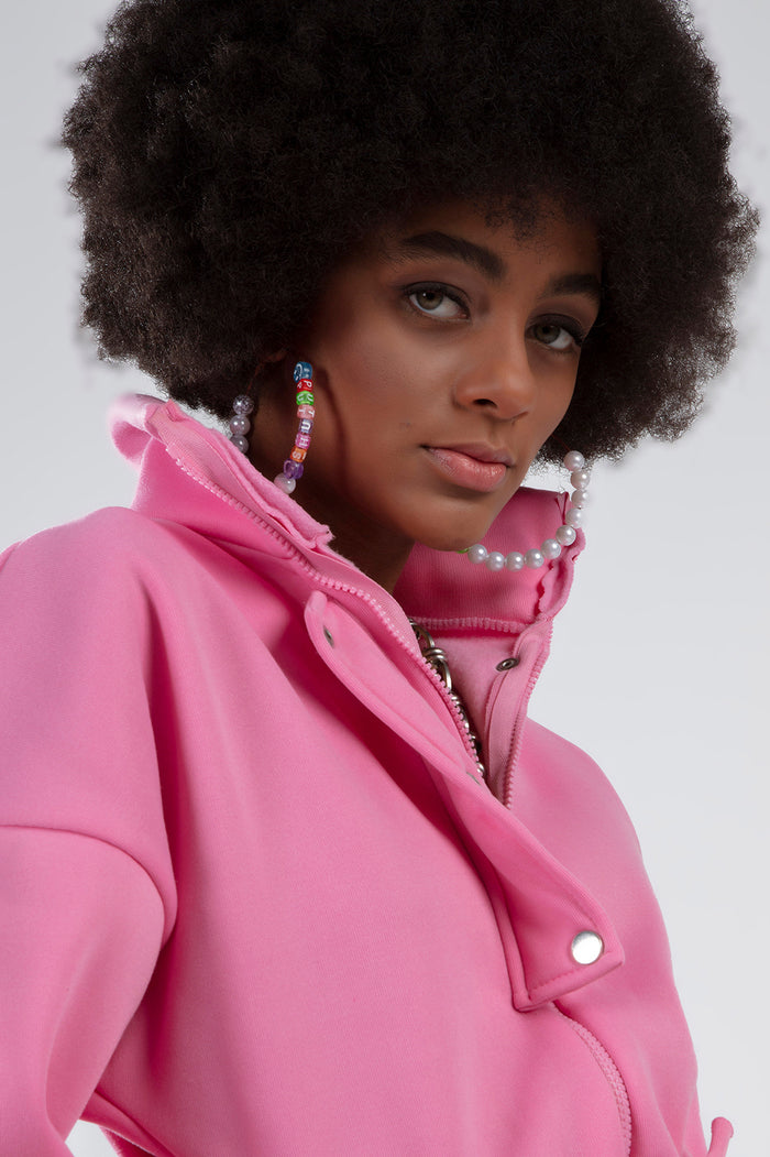 Close-up of the Gem Romper in pink featuring a high-collar zip front and snap buttons, worn with pearl hoop earrings.