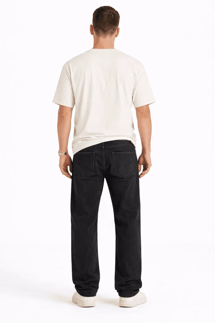 Rear view of a man wearing Black Baggy Fit Denim streetwear jeans in Carbon and a white t-shirt against a white background.