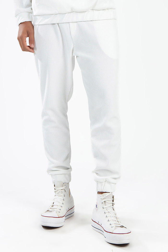 Close-up of white ribbed streetwear joggers and matching top from the Gordon two-piece set with white high-top sneakers.