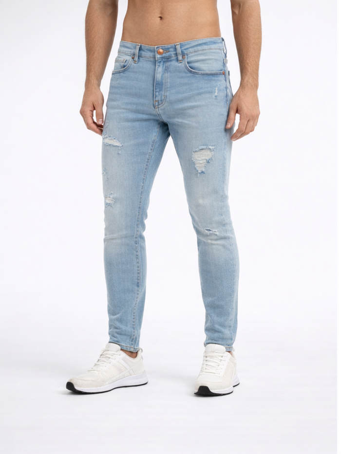 Light blue skinny jeans with distressed details, paired with white athletic shoes, worn by a male model.