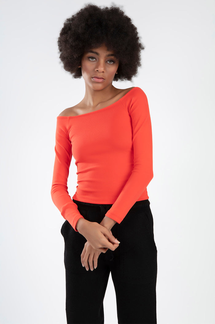 Model wearing a bright orange-red ribbed long sleeve off-the-shoulder top with black pants.