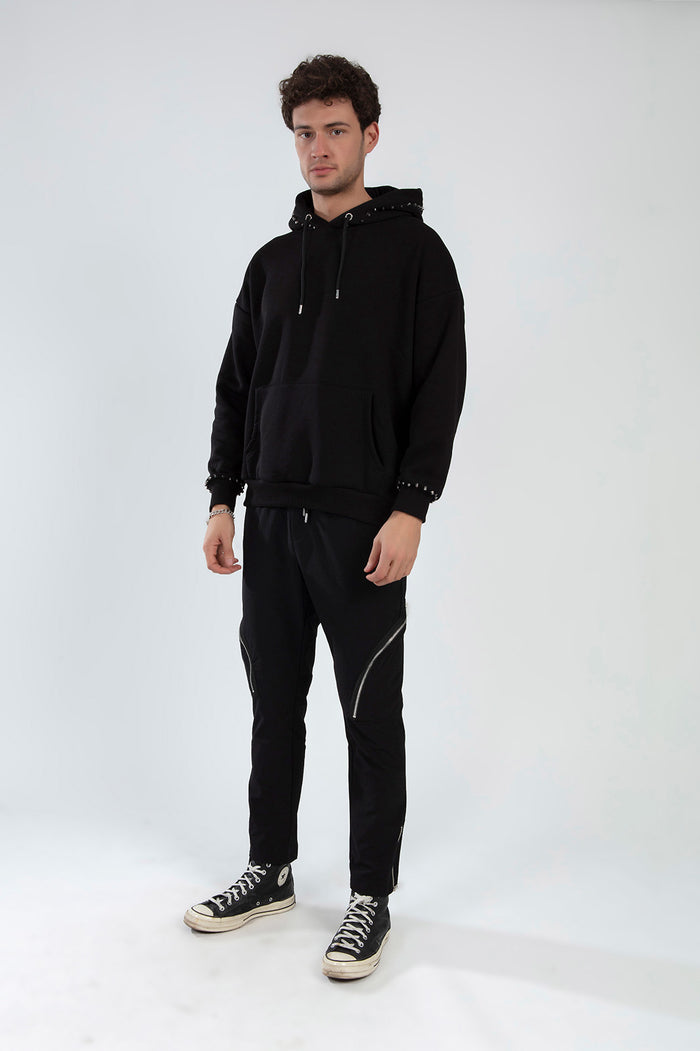 Men's Kent black slim fit pants with zipper details on the thighs, styled with a black hoodie and high-top sneakers.