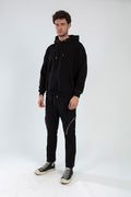 Men's Kent black slim fit pants with zipper details on the thighs, styled with a black hoodie and high-top sneakers.