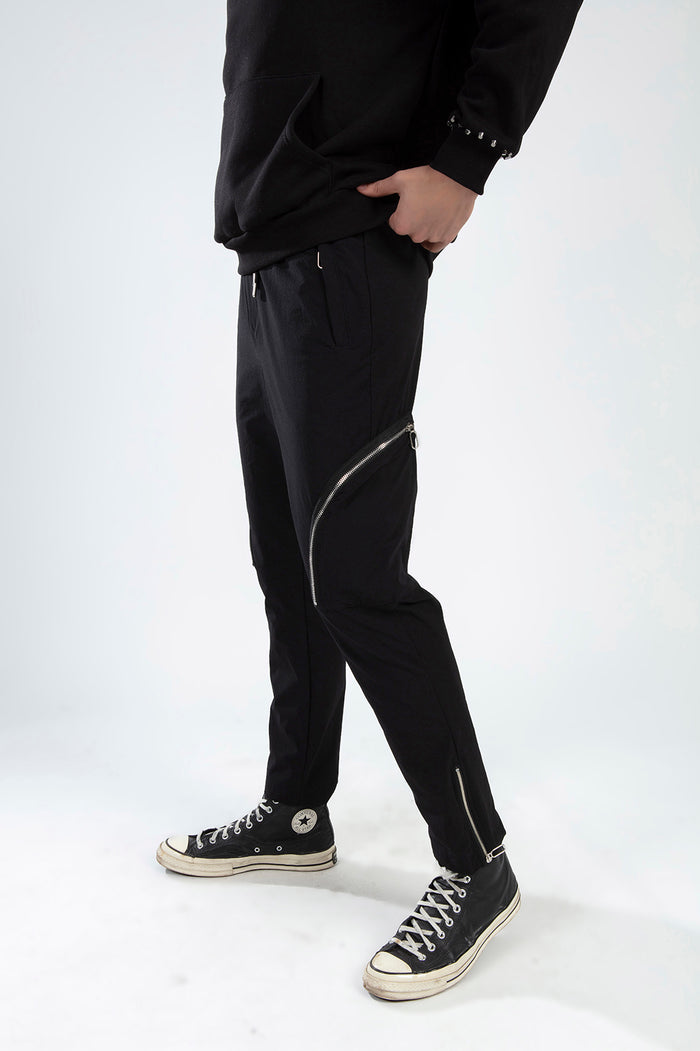 Model wearing Kent black slim fit streetwear pants with silver zipper details and tapered ankle zippers.