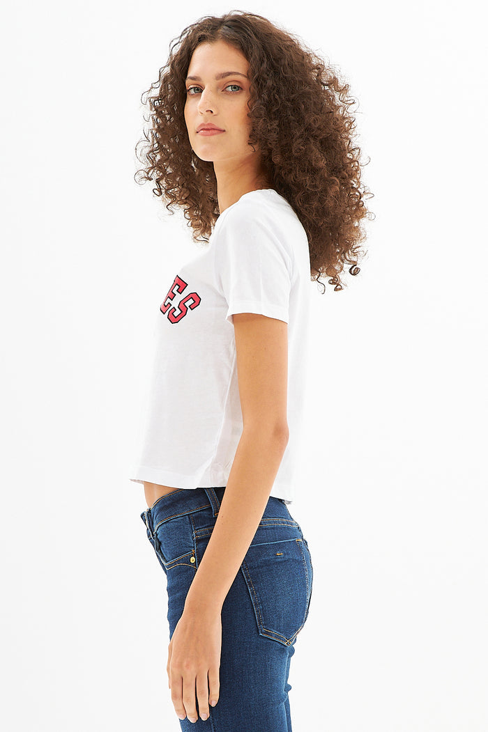 Side view of L.A. Vibes White Crop Top with red graphic on a model with curly hair, paired with dark blue jeans.
