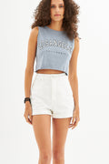 Woman in a blue-grey L.A. streetwear graphic tank top with raw hem and white high-waisted denim shorts.