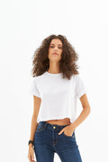 Model wearing Leah White Ribbed Crop Top, a short-sleeve boxy summer tee paired with dark wash denim jeans.