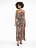 A model poses in a leopard print maxi dress with a thigh-high slit and strappy sandals.