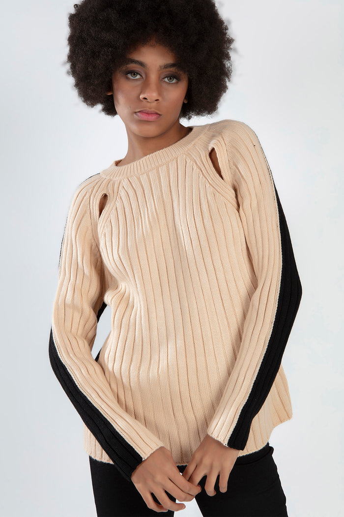Model in Lilith beige knit sweater with black sleeve stripes and shoulder cut-outs for a trendy fall aesthetic.